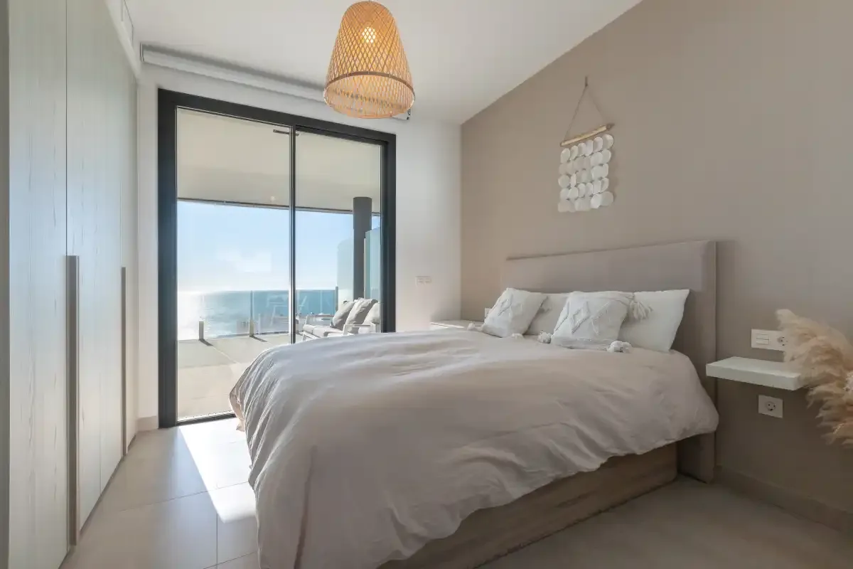 Un dormitorio con una cama y puertas corredizas de vidrio que dan a un balcón.