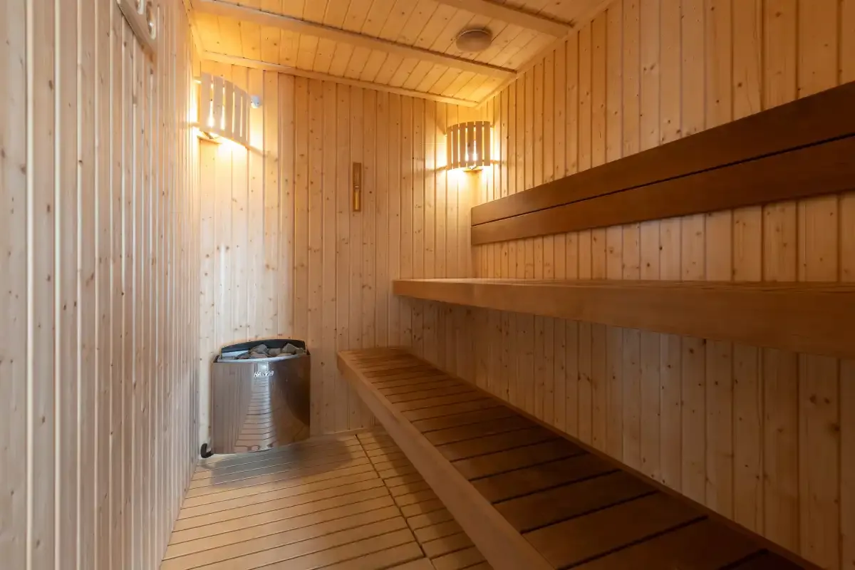 Una sauna revestida de madera con asientos escalonados y luces cálidas en la pared.