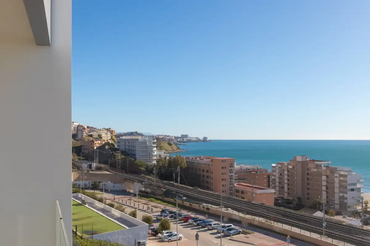 Desde un balcón se ven una ciudad costera y el mar.