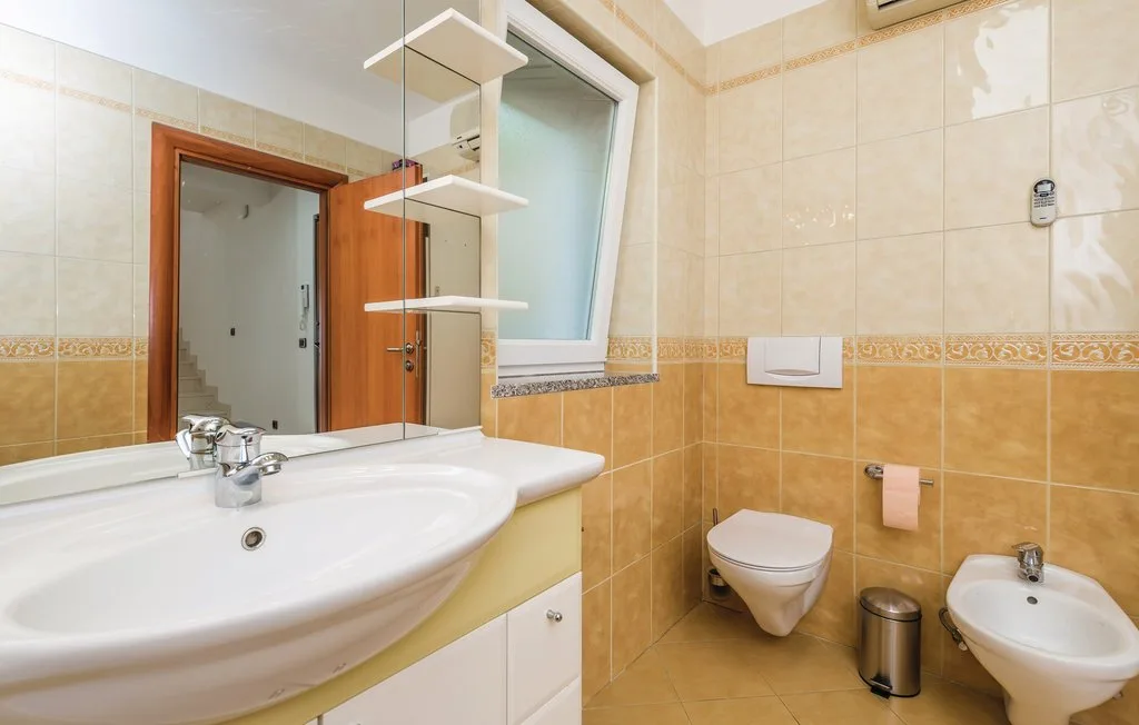 A tiled bathroom with a sink, toilet, and bidet.