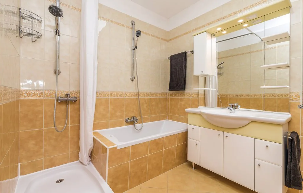 A tiled bathroom with a bathtub, separate shower, and vanity.