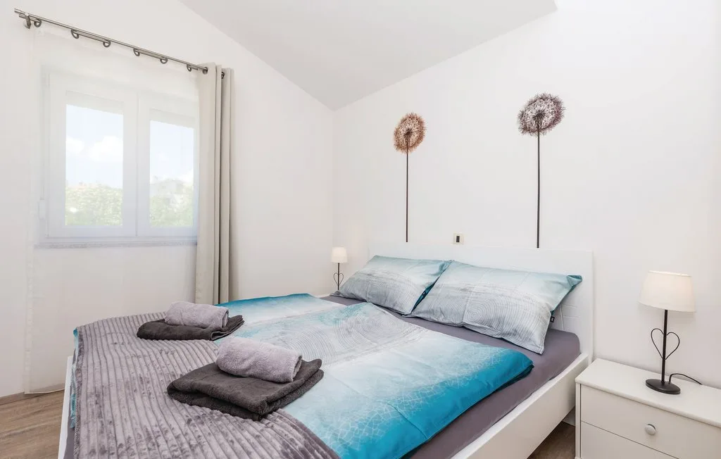A bright bedroom with a large bed beneath two simple wall decorations.