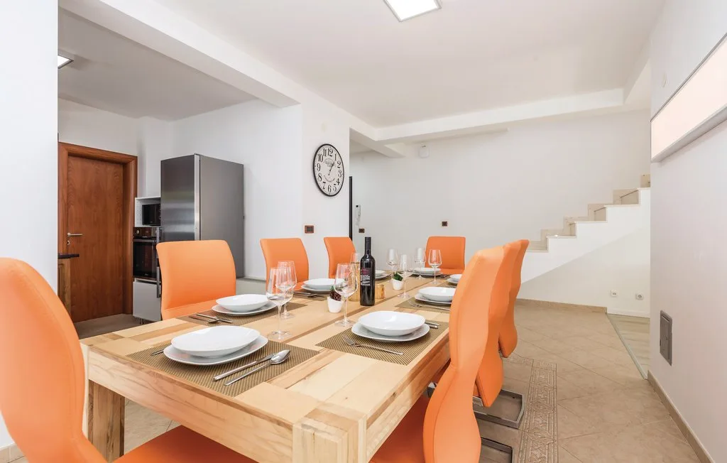 A dining area with a wooden table, orange seating, and a staircase.