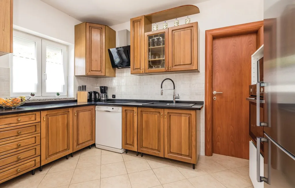 A kitchen with wooden cabinets, dark countertops, and a window.
