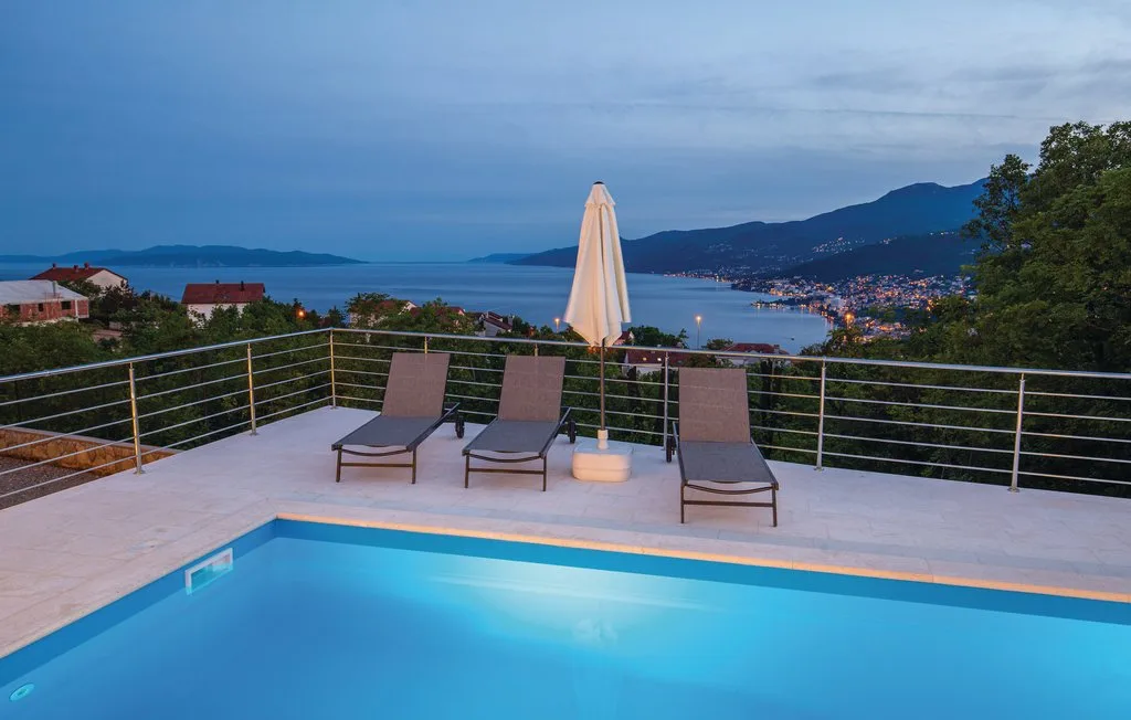 A rooftop pool terrace overlooks the sea, with lounge seating and an umbrella.