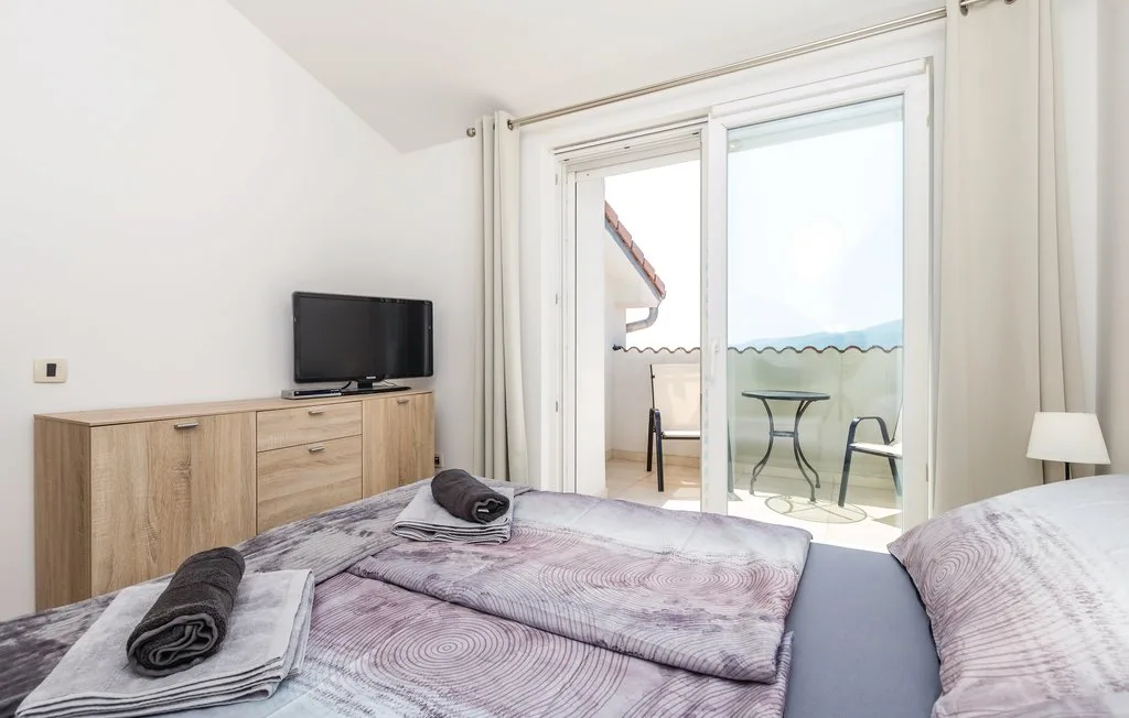 Bedroom with a bed, wooden dresser, and sliding glass doors opening onto a patio.