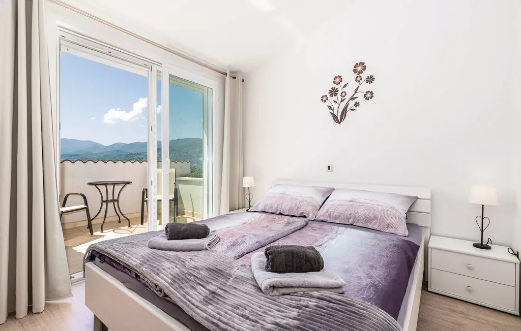 A bedroom with a double bed beside glass doors opening onto a balcony.