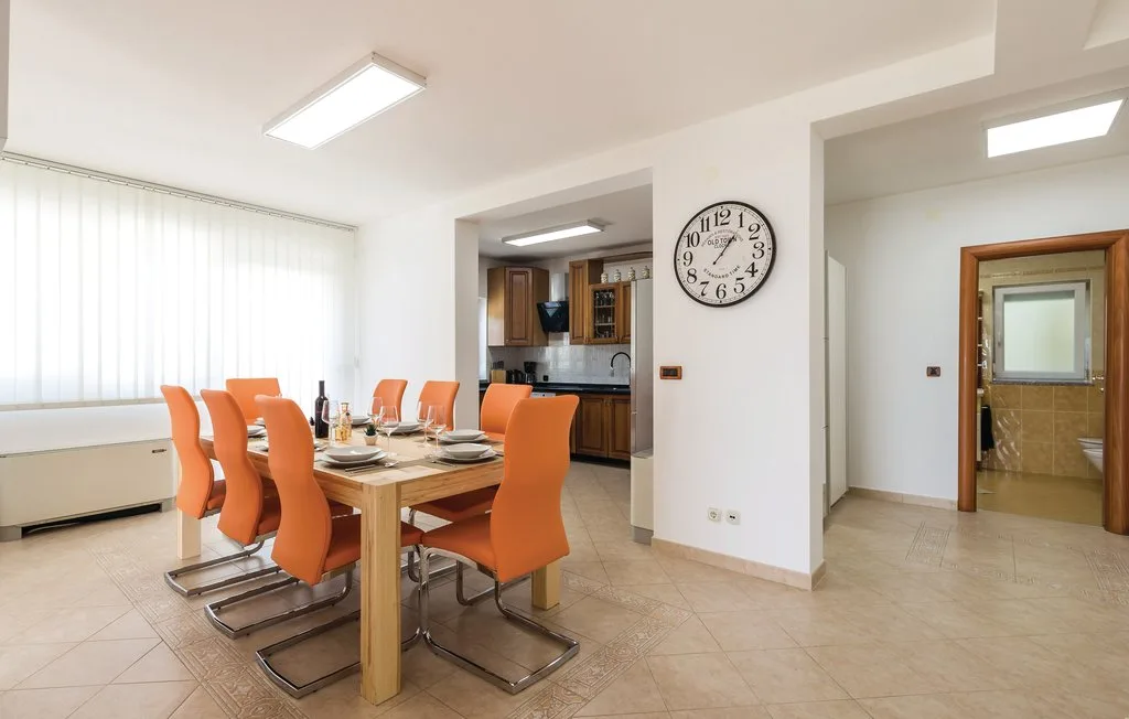 A dining area with a wooden table and orange seating beside a kitchen.
