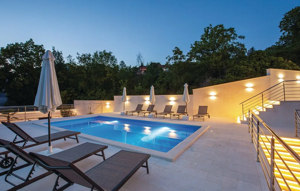An outdoor pool area with lounge seating and trees in the background.