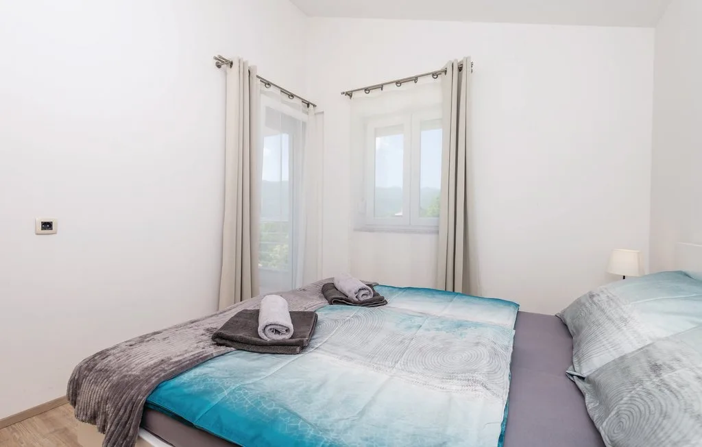 A bright bedroom with beds dressed in pale blue bedding.