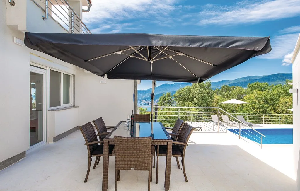 A patio dining area with a table and seating beneath a large umbrella.