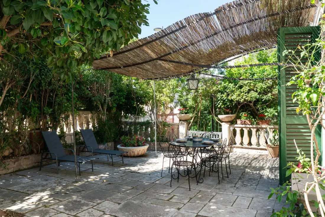 Un patio de jardín sombreado tiene asientos al aire libre bajo un toldo tejido.