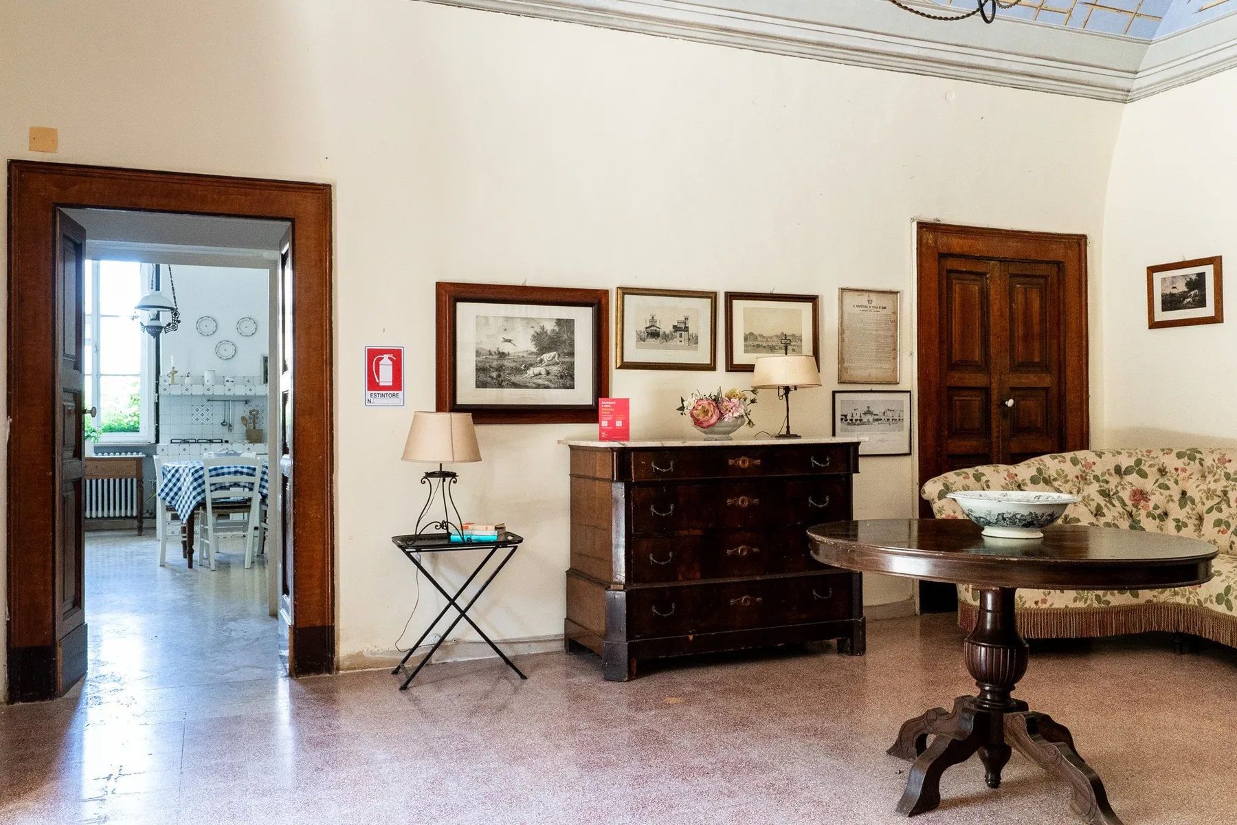 Una sala amueblada con cuadros enmarcados y una puerta hacia un comedor.
