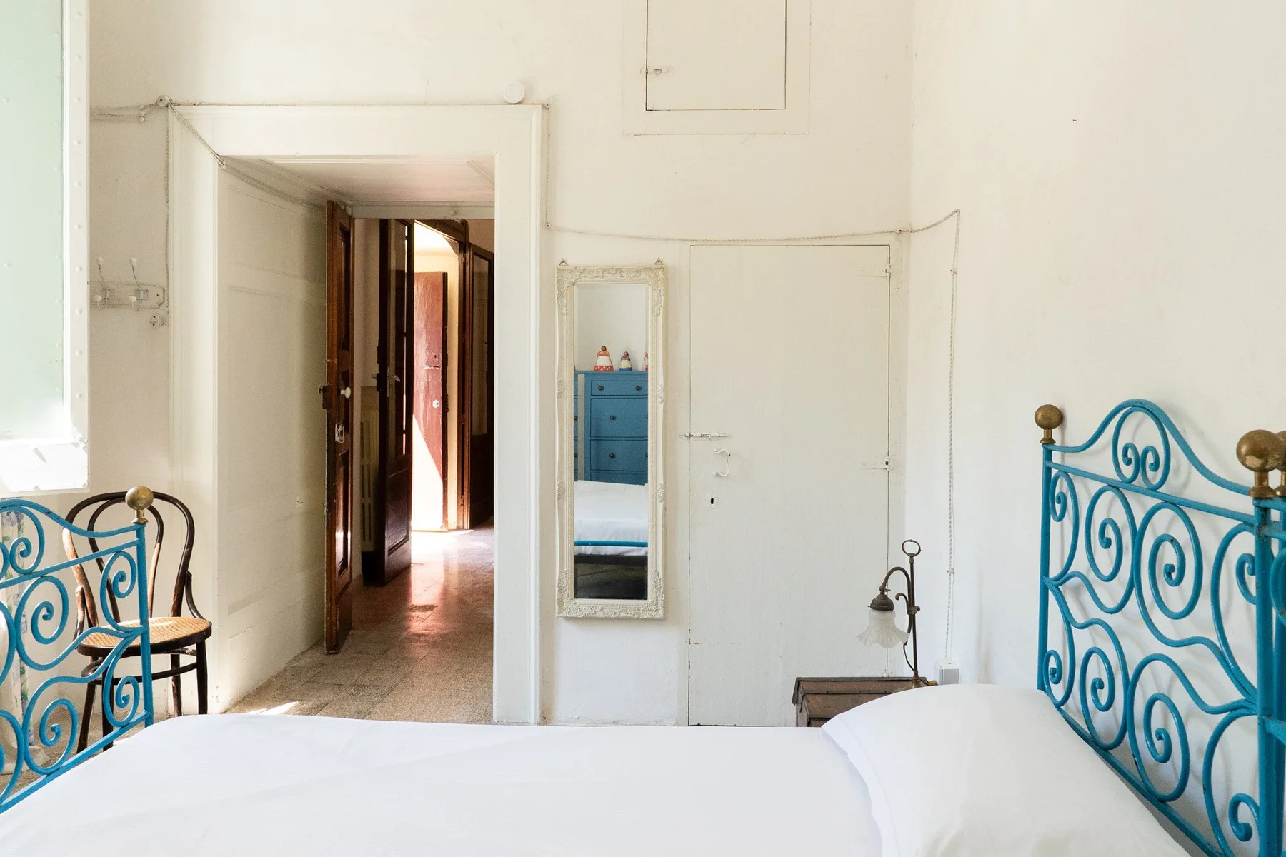 Un dormitorio con una cama blanca y cabeceros de metal azul decorados.