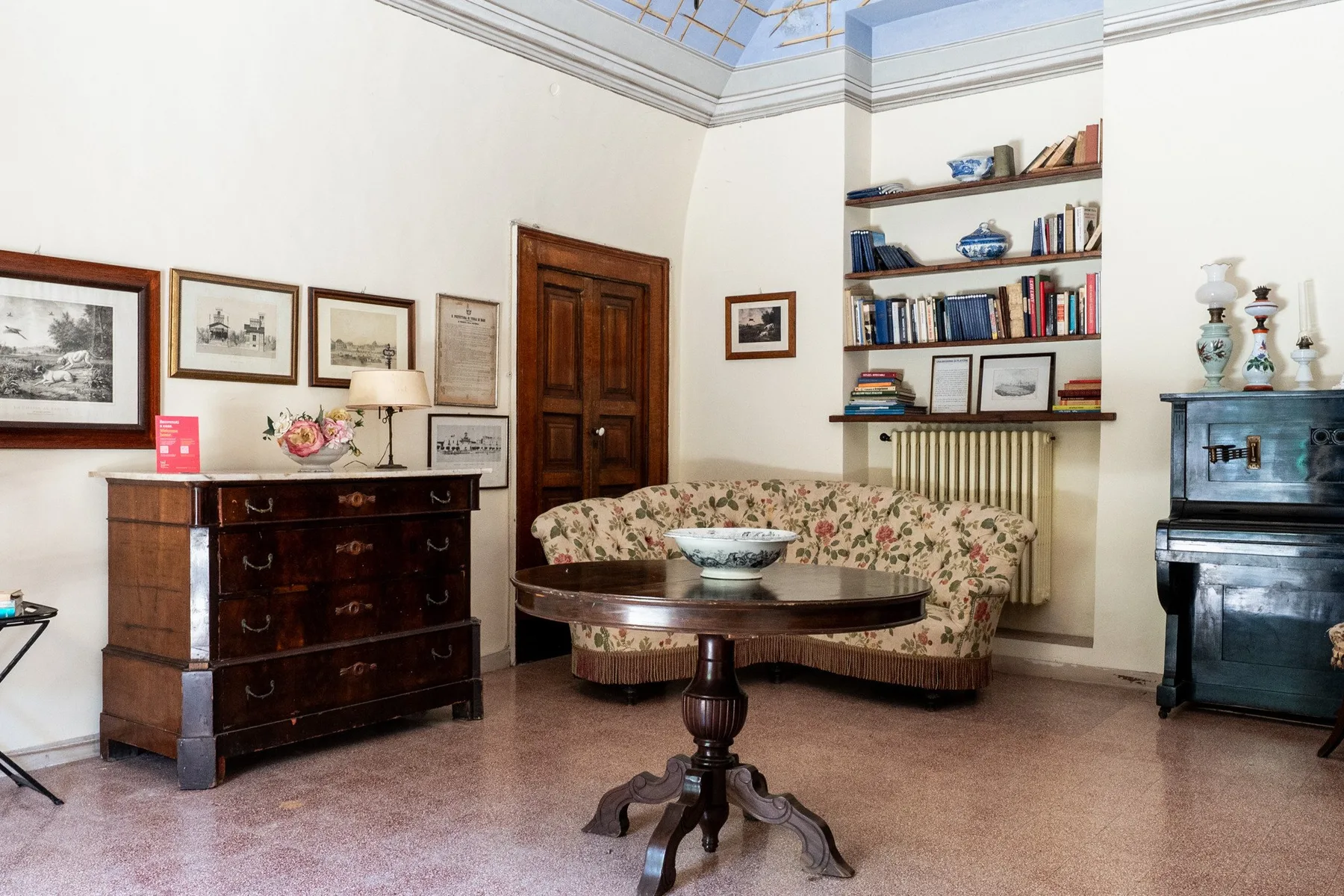 Una sala de estar luminosa con asientos florales, una mesa de madera y estanterías.