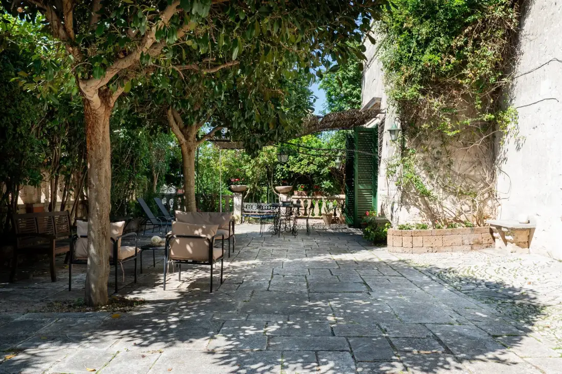 Un patio exterior sombreado con asientos y un camino de piedra.