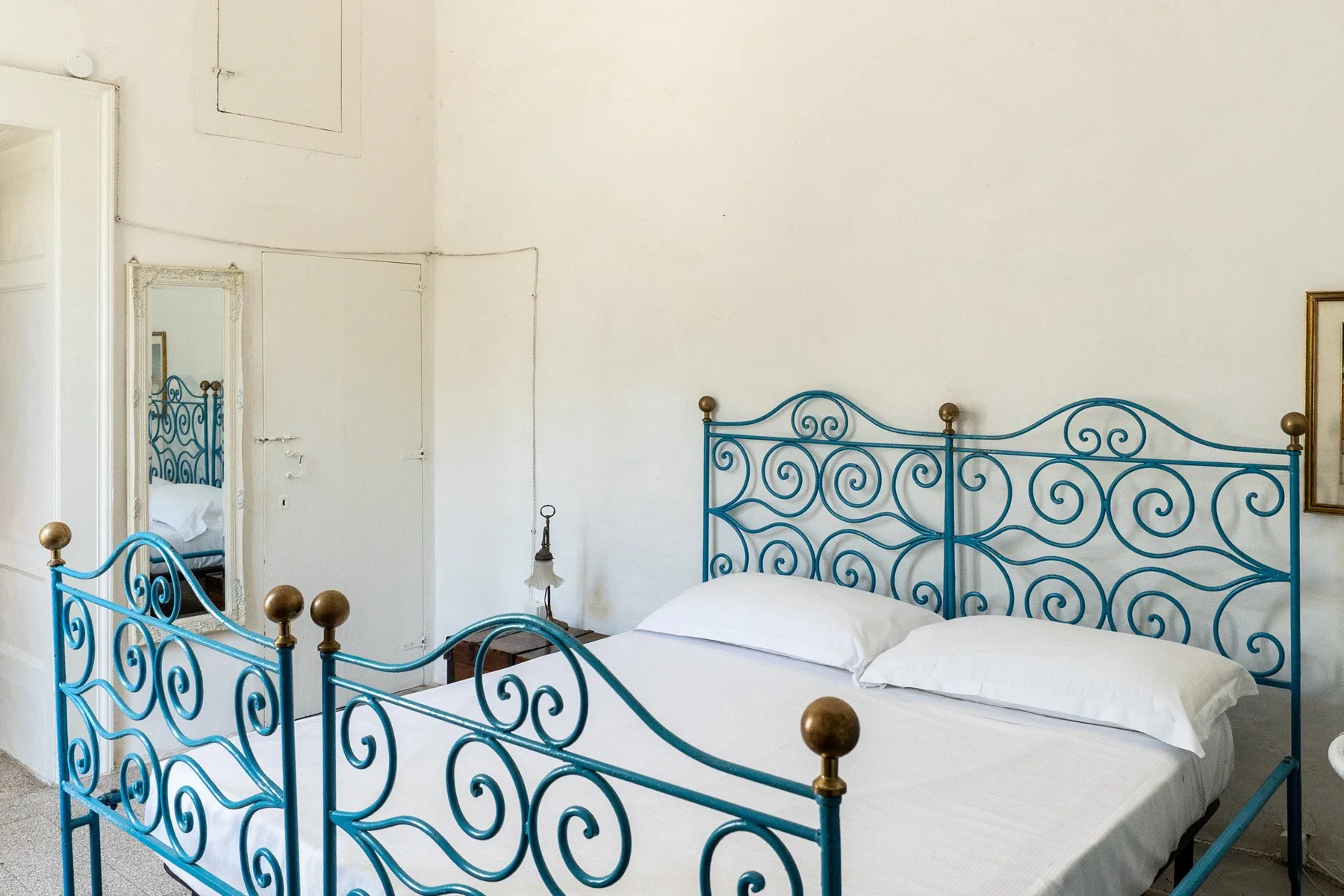 Un dormitorio con una cama enmarcada por barandillas metálicas azules ornamentadas.