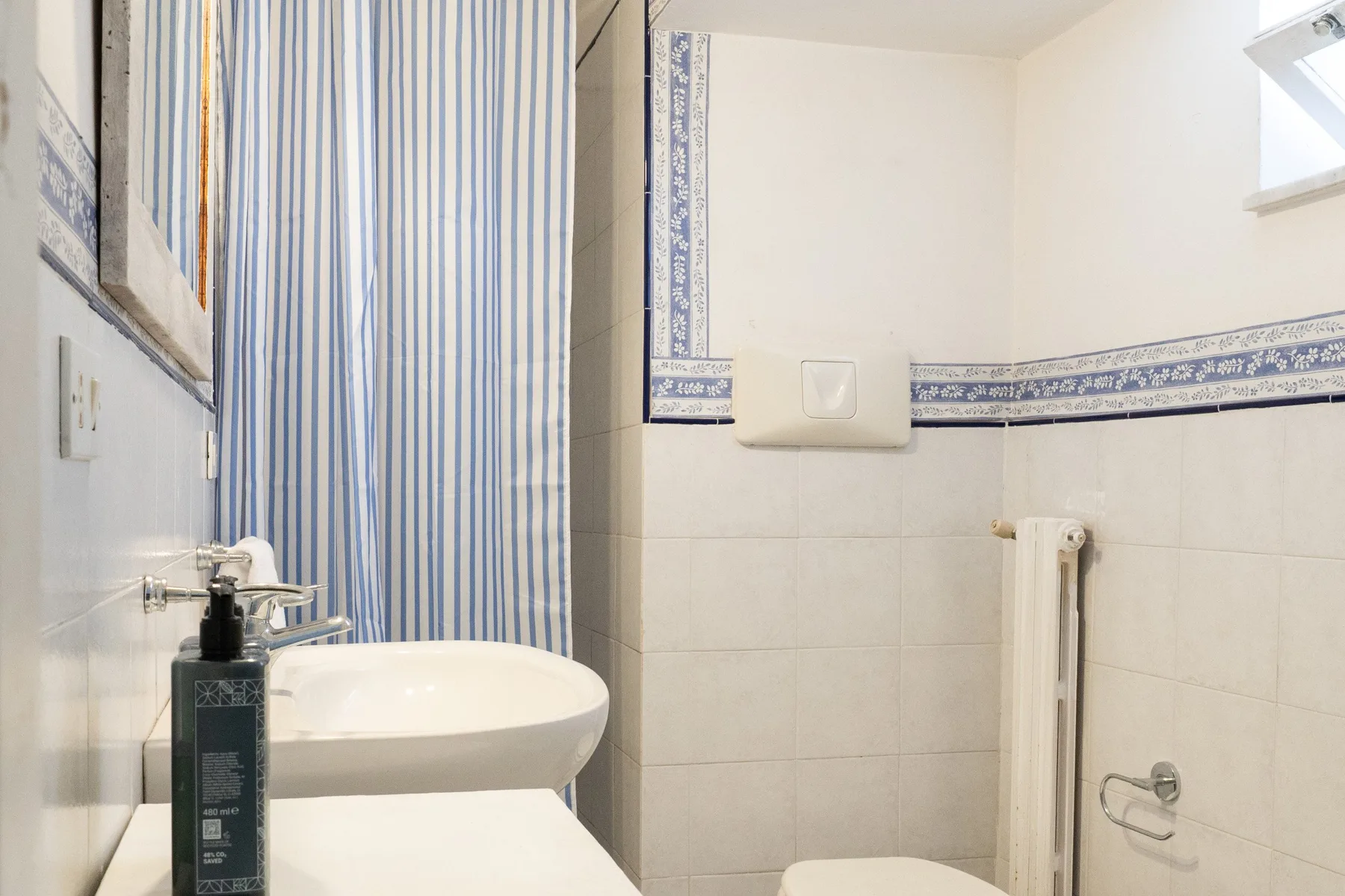 Un baño con lavabo, inodoro y cortina de ducha a rayas azules y blancas.