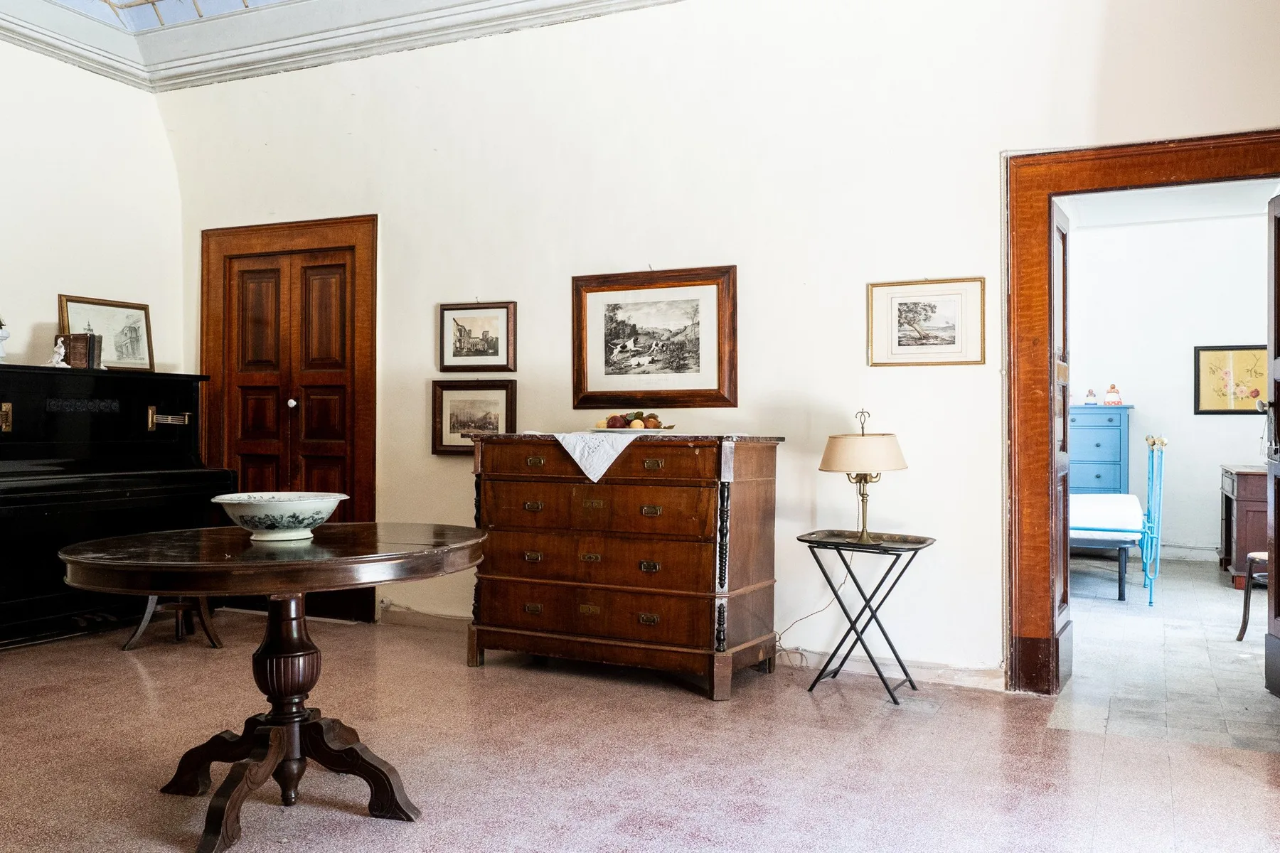 Una sala luminosa con un piano, muebles de madera y cuadros enmarcados.