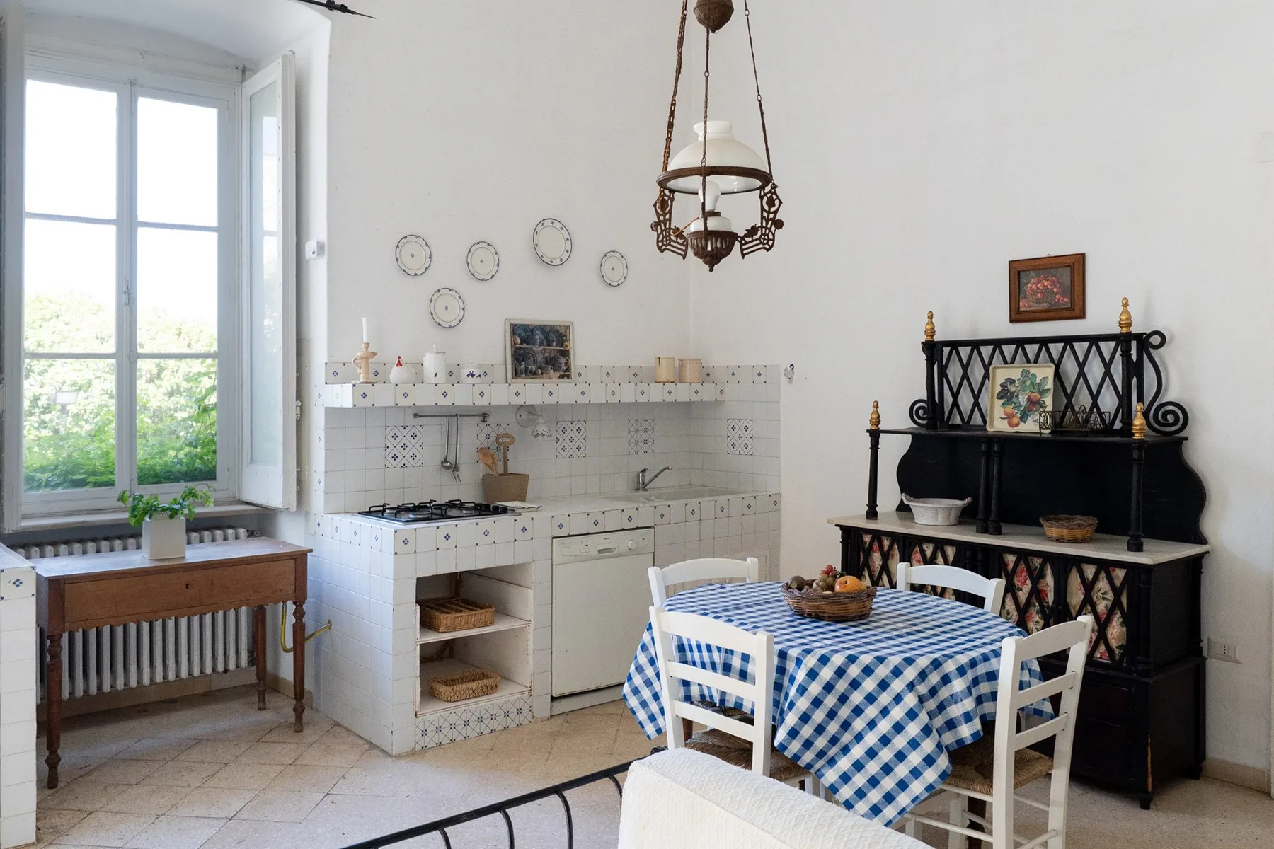 Un comedor luminoso con un mantel de cuadros azules y blancos y una ventana grande.