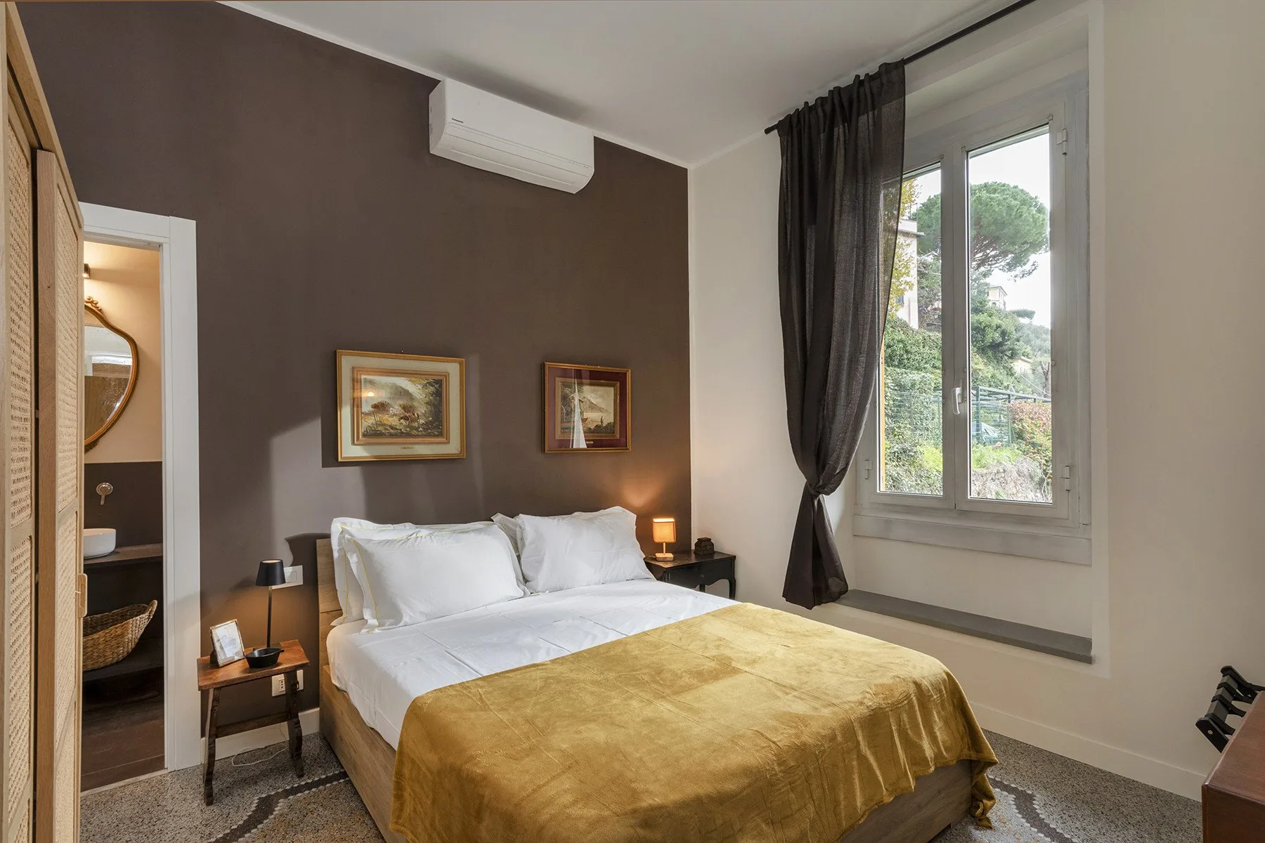 Un dormitorio con una cama, mesitas de noche y una ventana grande.