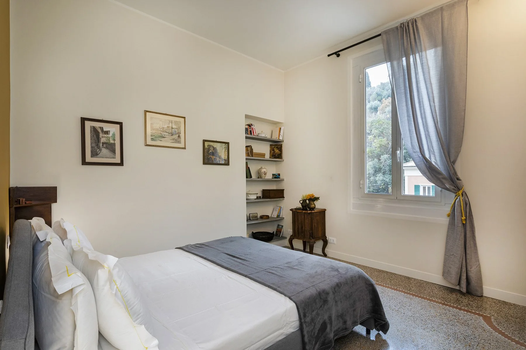 Un dormitorio con una cama bien arreglada y una gran ventana con cortinas.