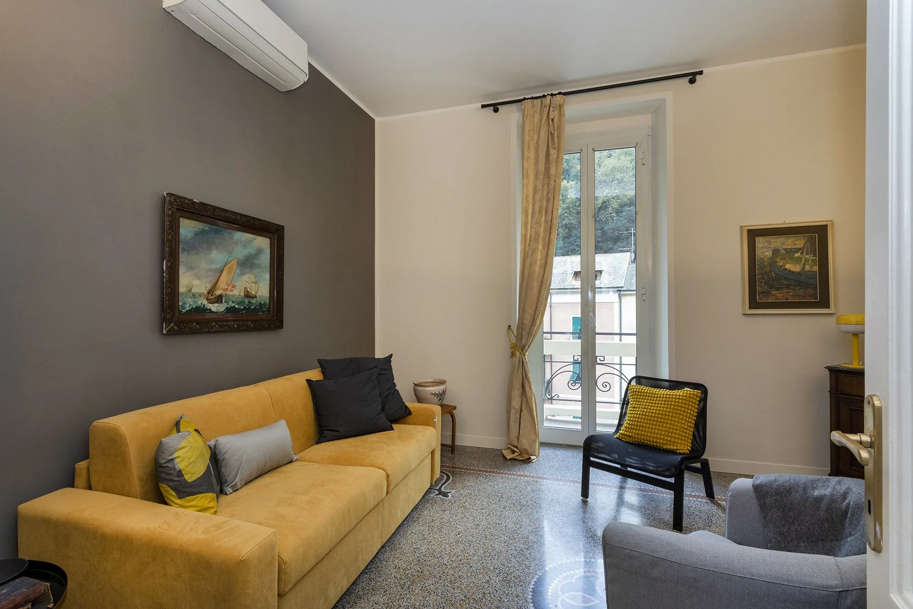 Una sala de estar con un sofá amarillo y una puerta de vidrio que da a un balcón.