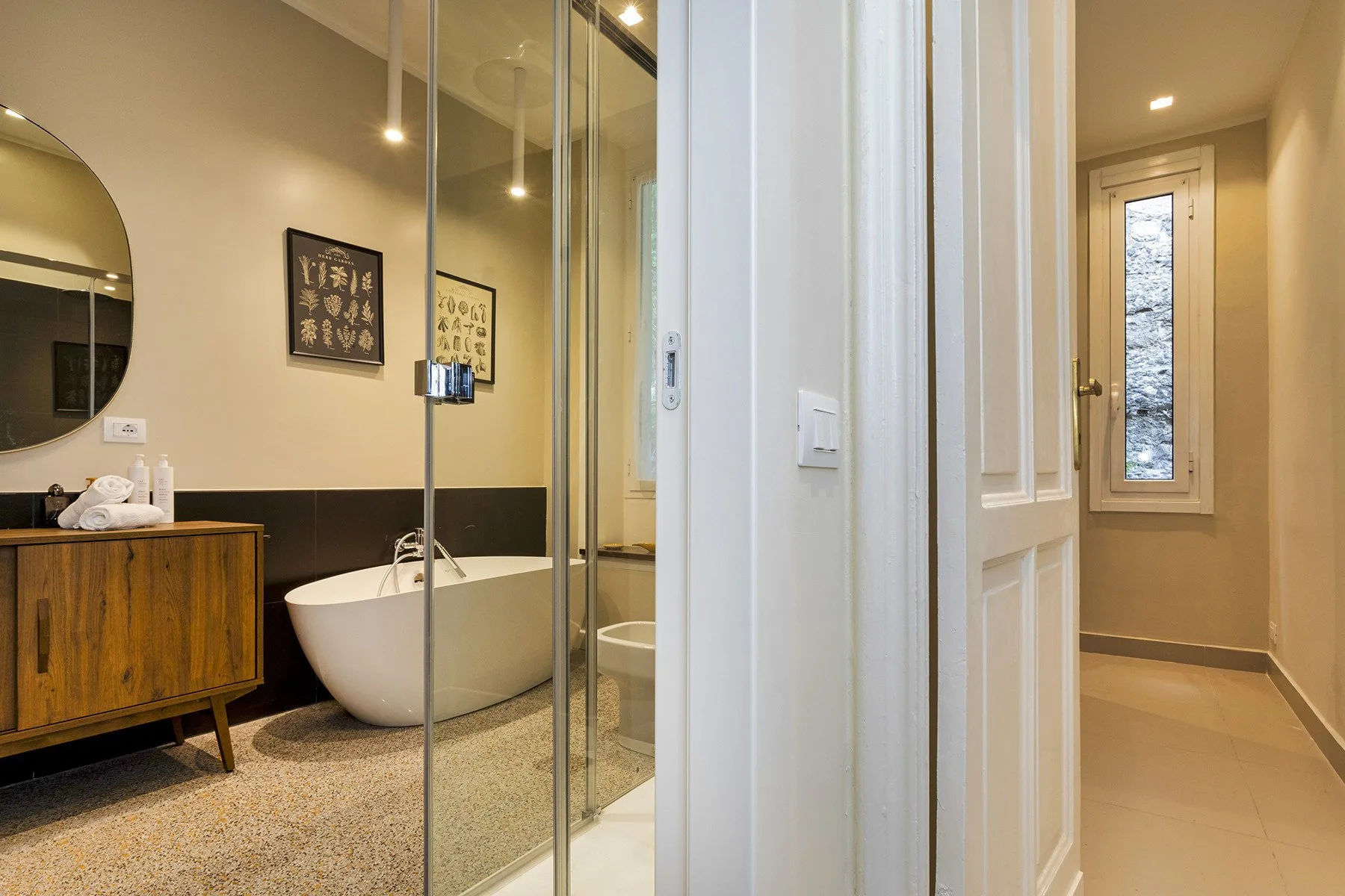 Un baño con una bañera exenta y paneles de vidrio para la ducha.