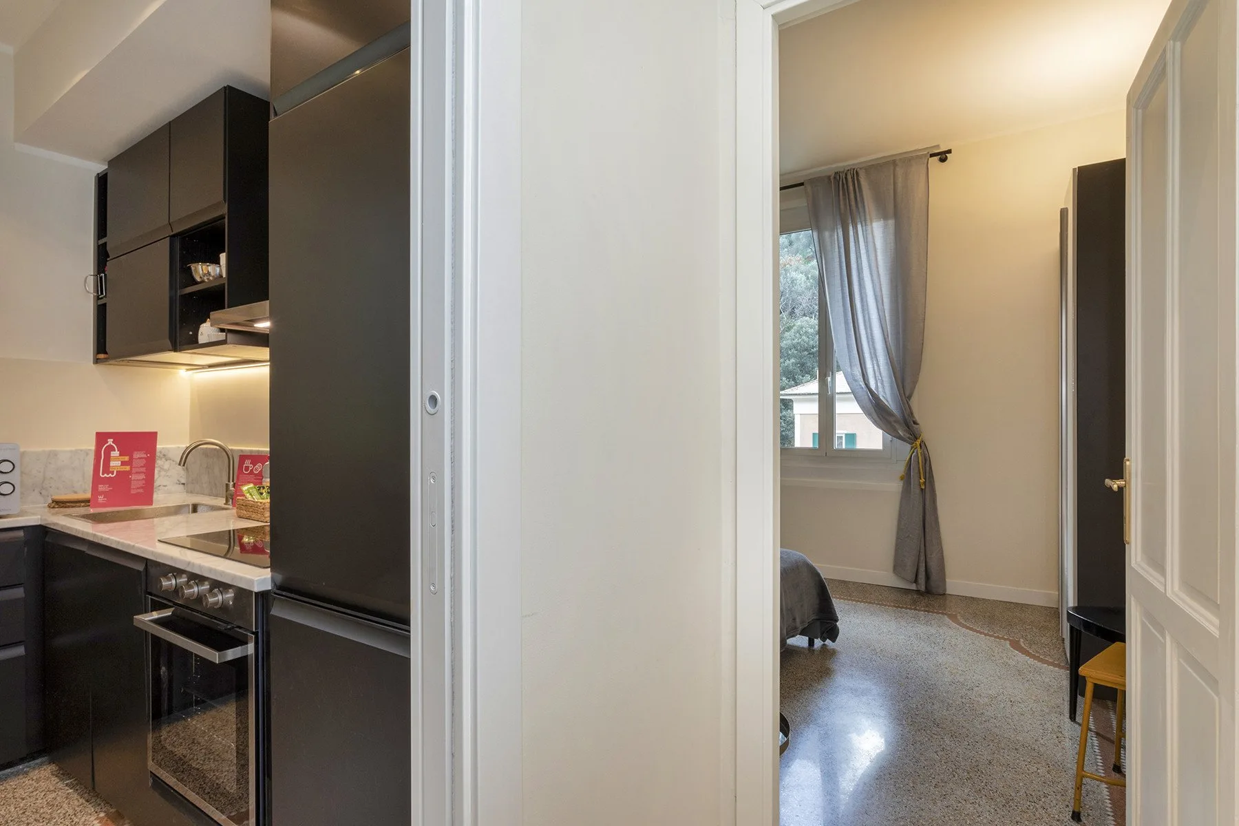 Se ven una cocina y una habitación contigua a través de una puerta abierta.