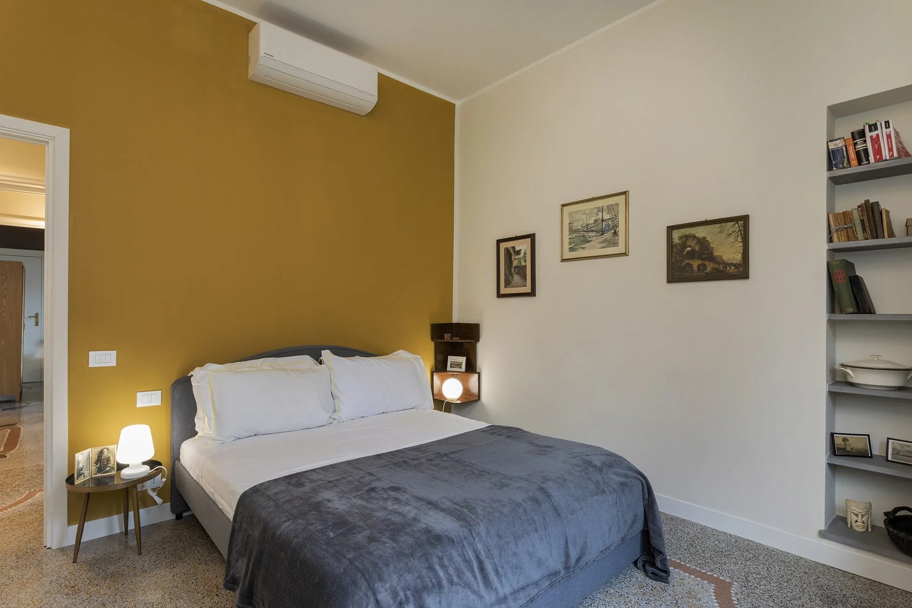 Un dormitorio con una cama doble junto a una pared color mostaza.