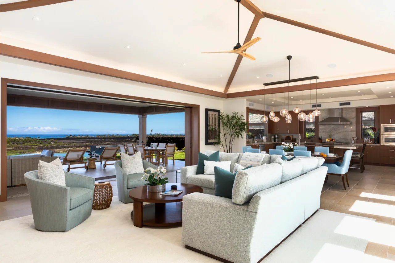 Una sala de estar de concepto abierto con asientos, comedor y amplias ventanas con vistas al agua.