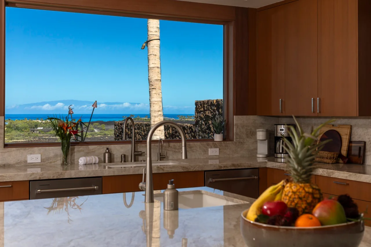 Una cocina con una amplia ventana con vistas al mar y un frutero sobre la encimera.