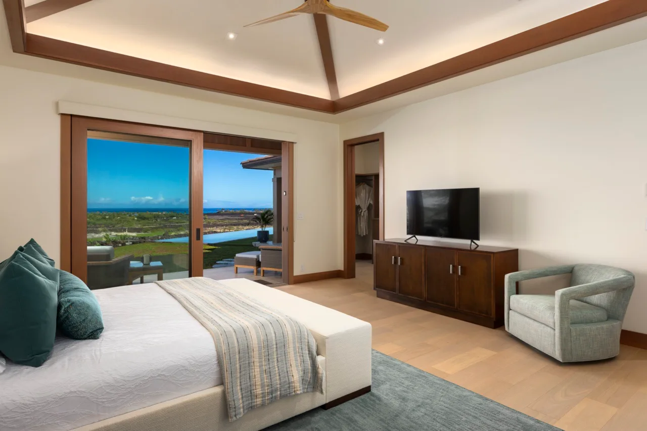 Un dormitorio con cama, televisor y puertas corredizas de vidrio que dan a un balcón.