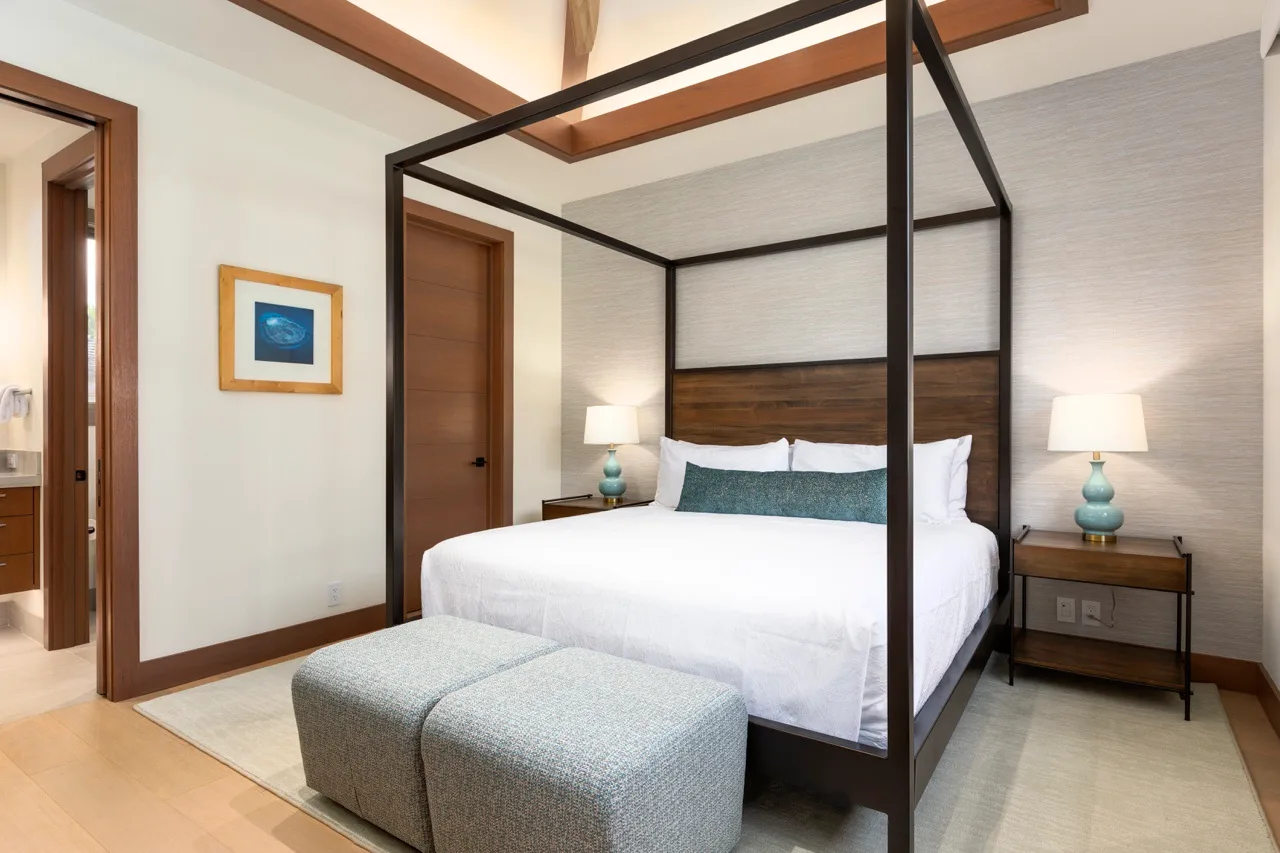 Un dormitorio con una cama con dosel oscuro y asientos tapizados a los pies.