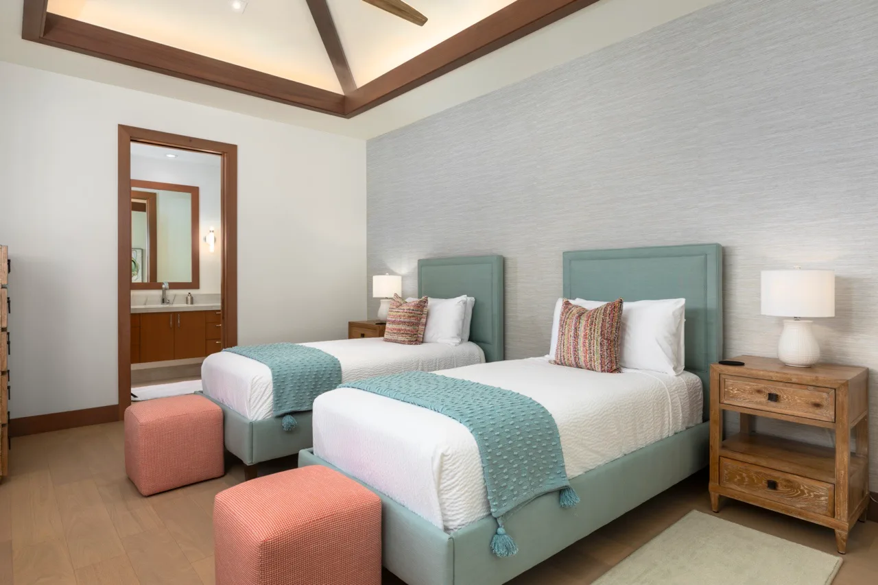 Un dormitorio con dos camas, ropa de cama color verde azulado y mesitas a juego.