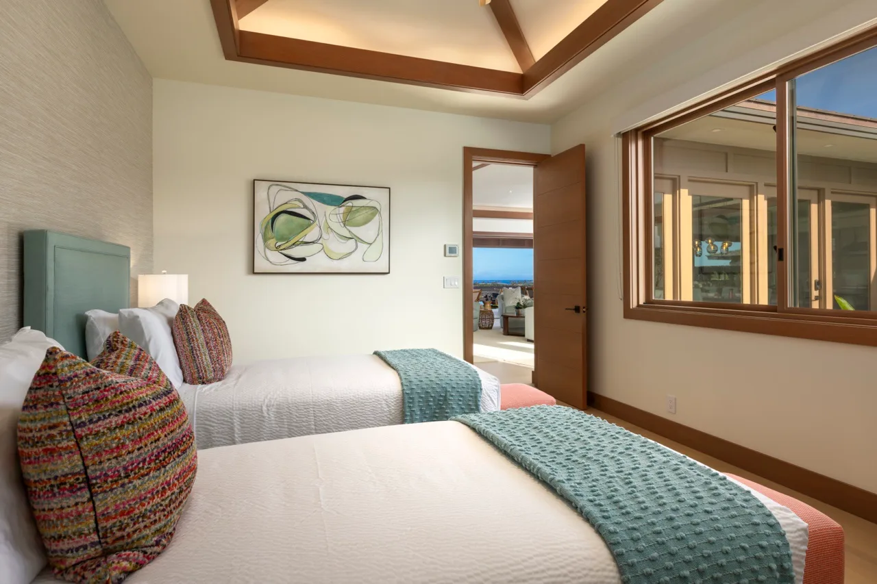 Un dormitorio con dos camas, colchas color turquesa y una ventana amplia.