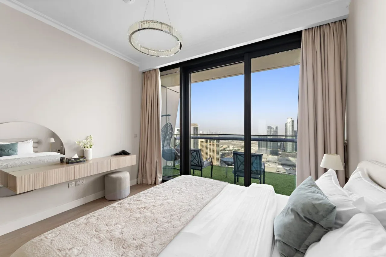 Un dormitorio con una cama grande junto a ventanales que dan a un balcón.