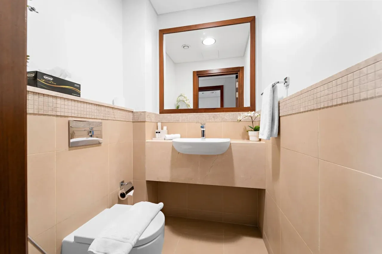 Un baño con lavabo, espejo e inodoro.