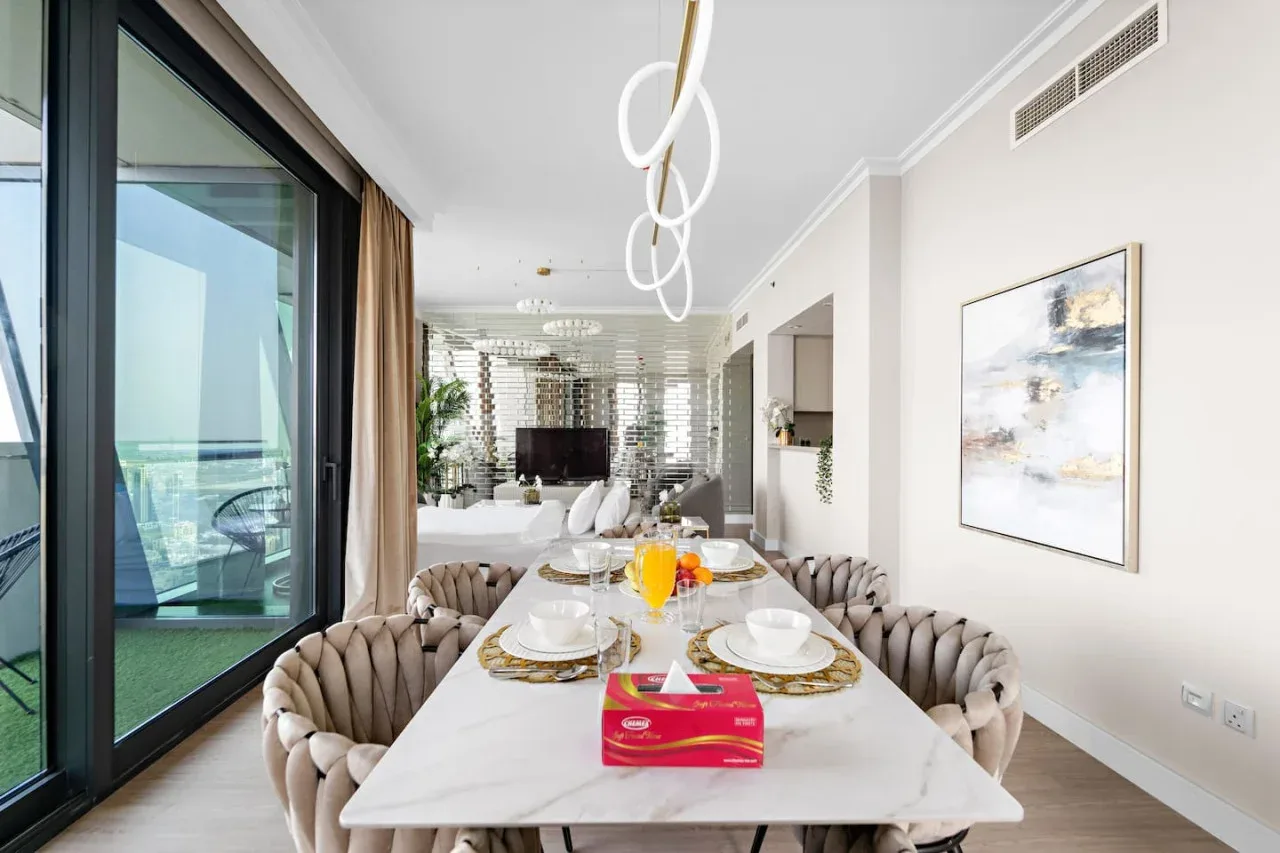 Comedor con una mesa larga puesta con platos junto a grandes puertas de vidrio.