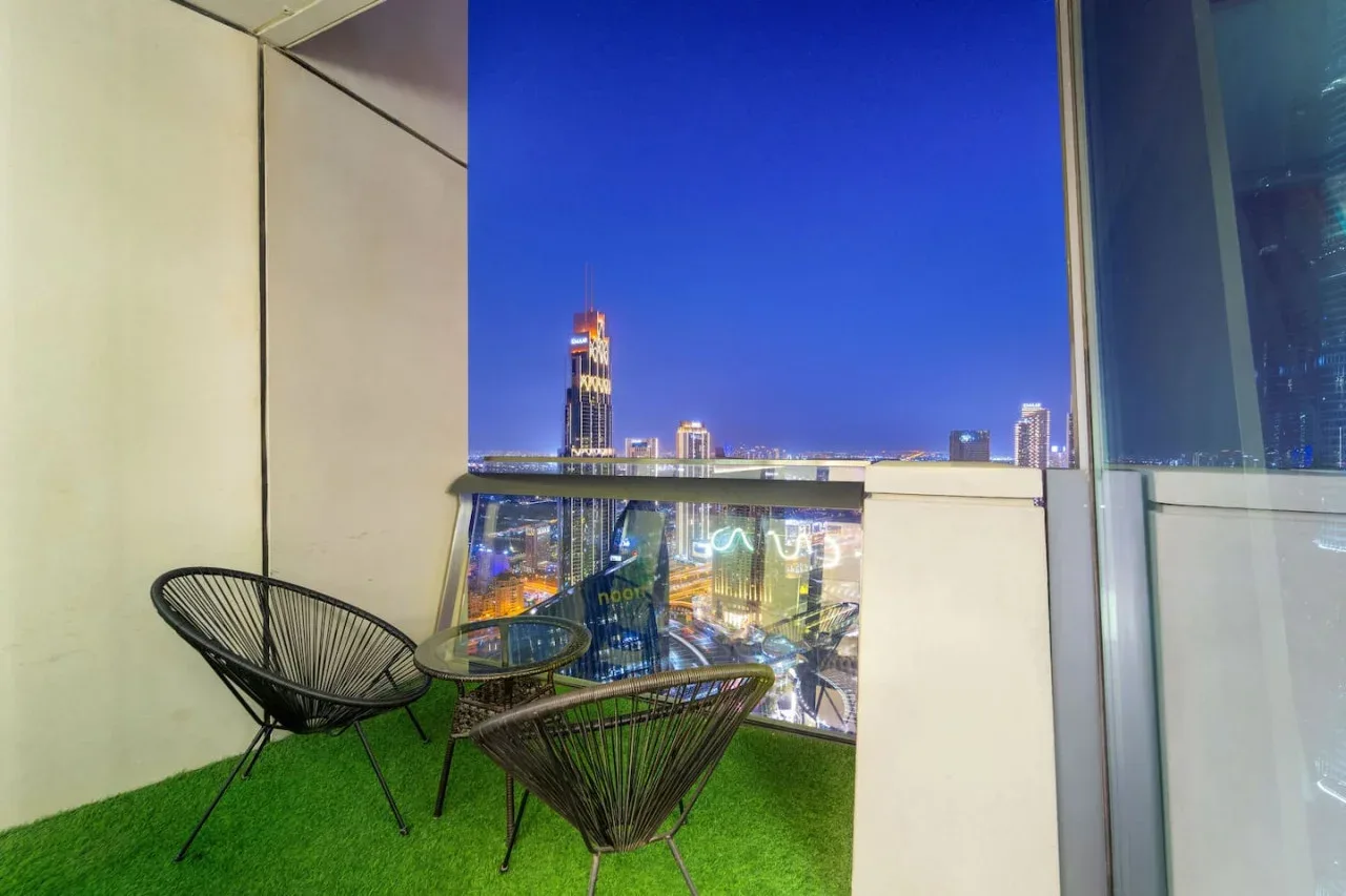 Una zona de asientos en un balcón ofrece vistas de edificios iluminados por la noche.