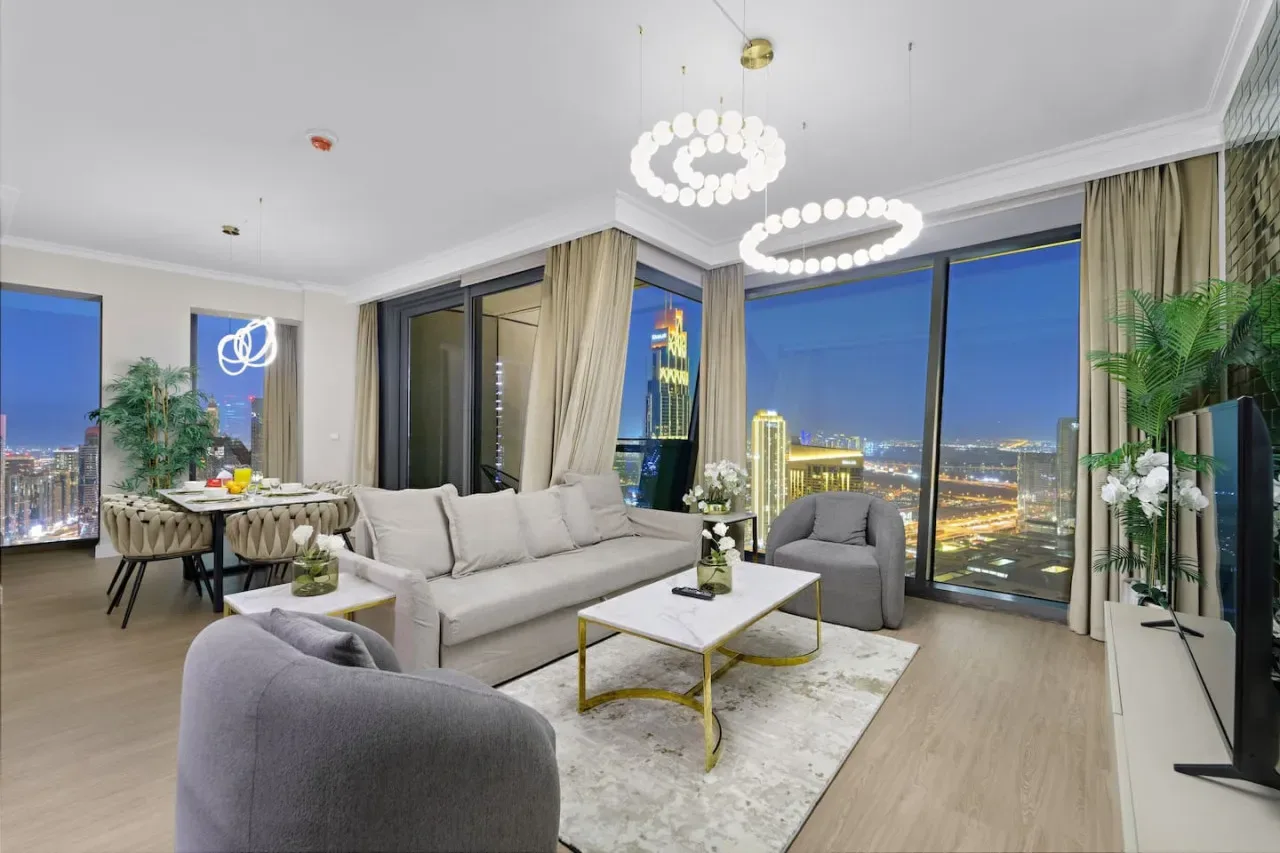 A modern living room with seating, a coffee table, and large windows overlooking the city.