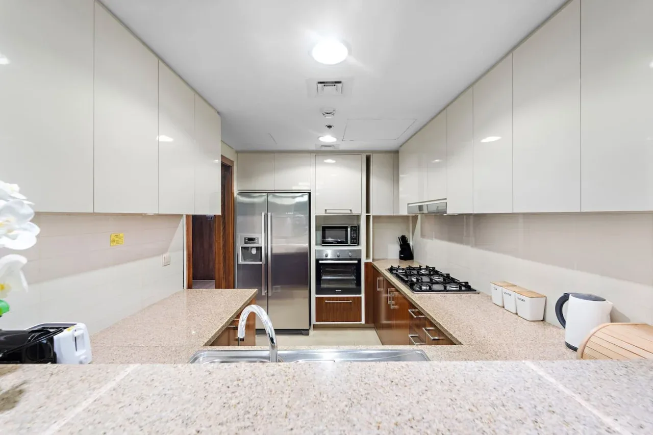 Una cocina luminosa con isla central, electrodomésticos de acero inoxidable y encimeras claras.