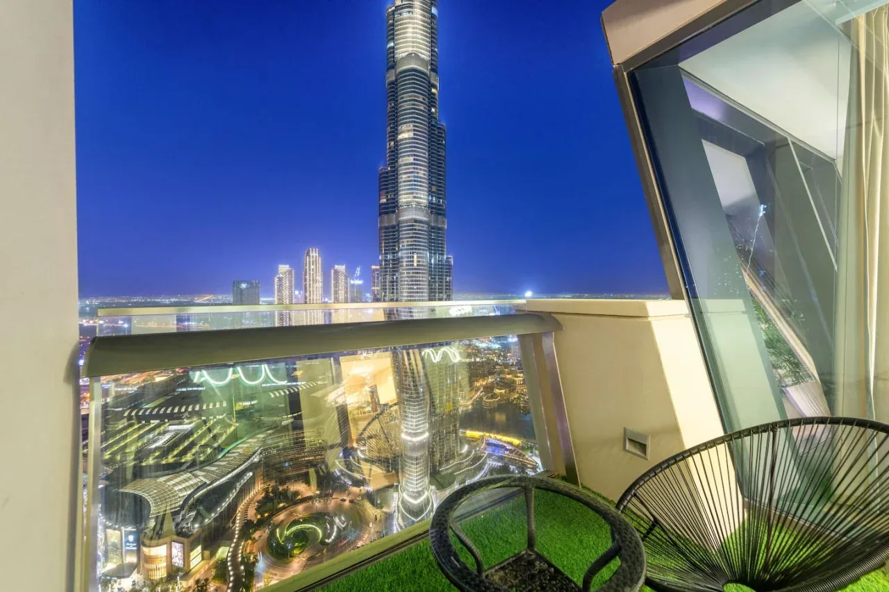 Un balcón ofrece vistas del Burj Khalifa iluminado y la ciudad de noche.