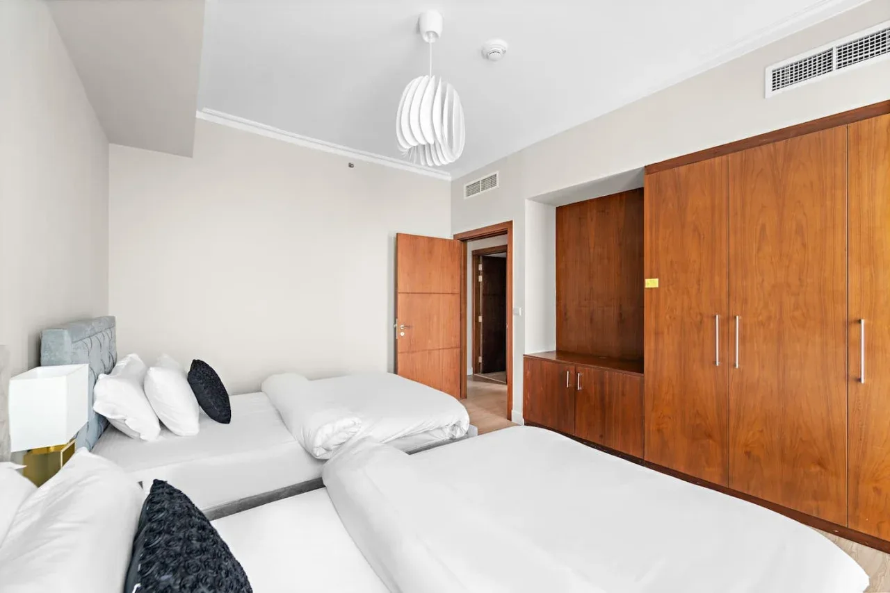 Un dormitorio luminoso con dos camas y armarios empotrados de madera.