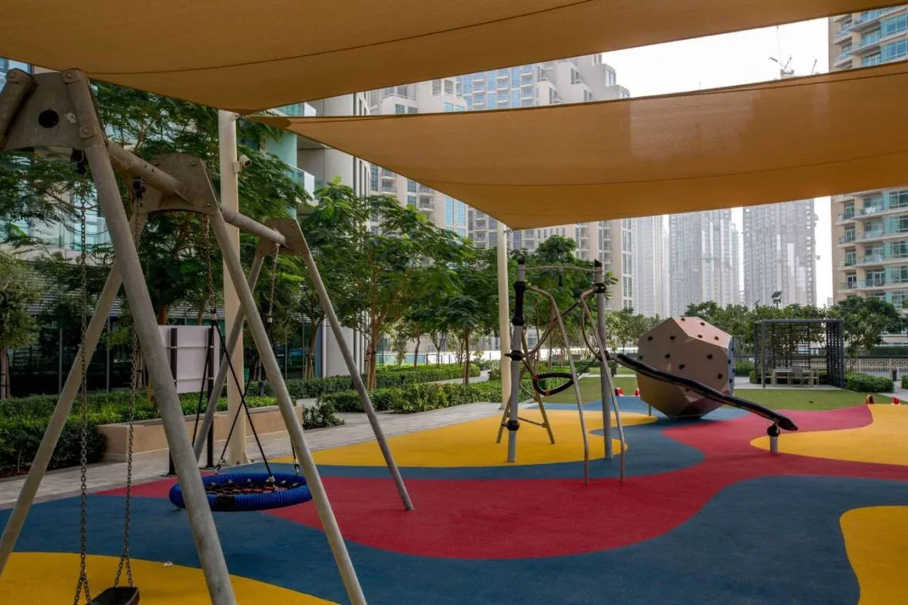 Un colorido parque infantil al aire libre con juegos para trepar bajo toldos de sombra.