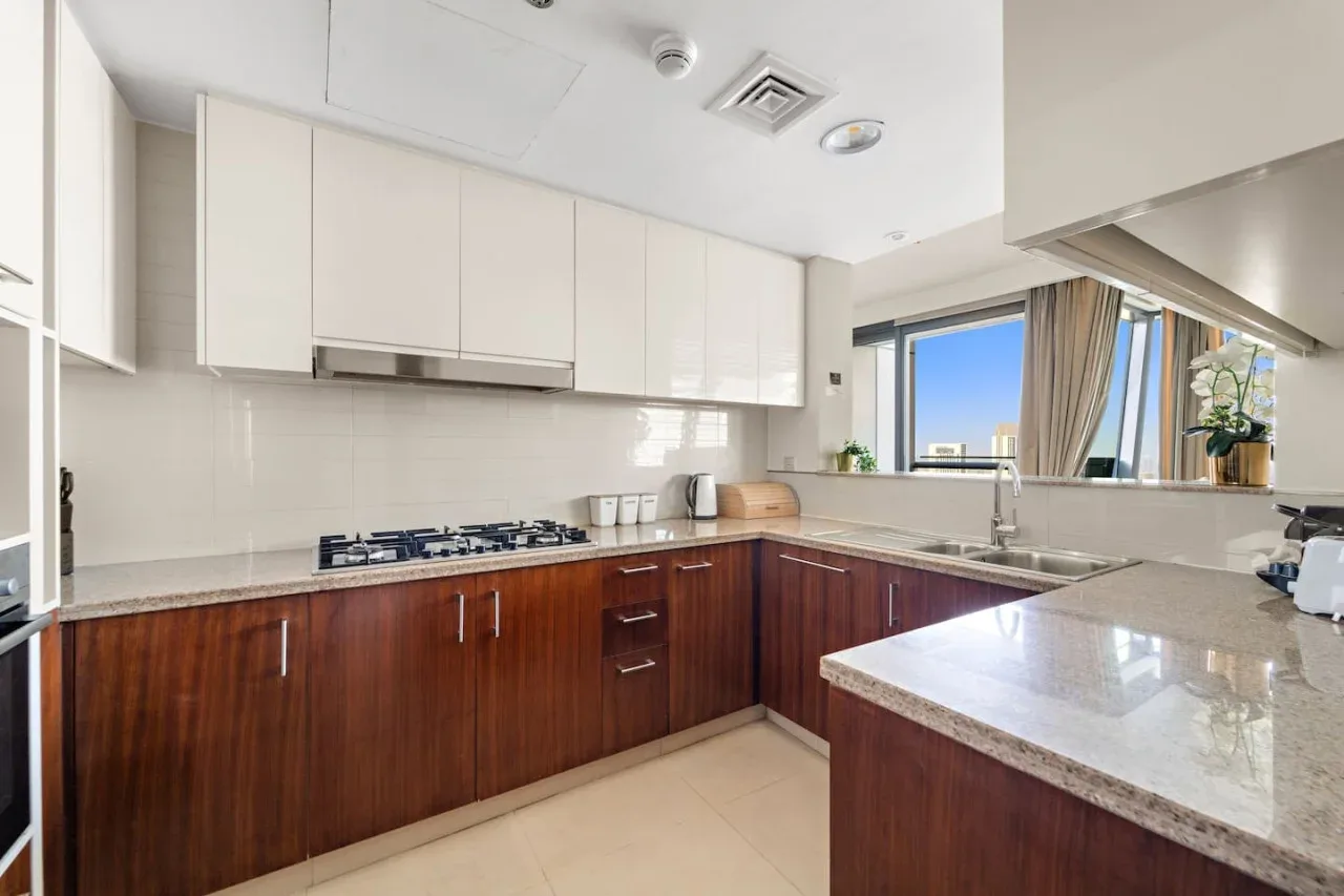 Una cocina luminosa y moderna con una encimera en forma de L y armarios inferiores de acabado de madera.