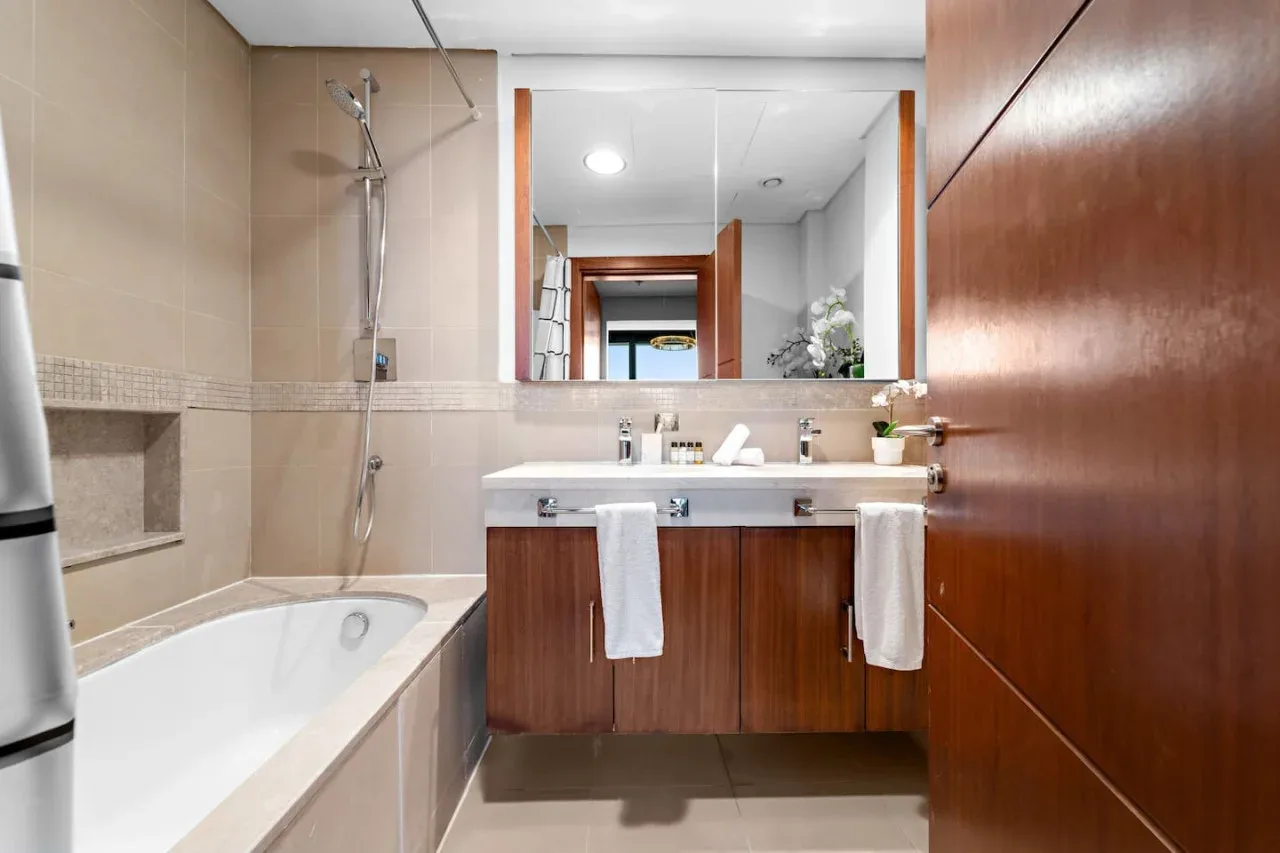 Un baño con bañera, ducha y lavabo bajo un espejo grande.