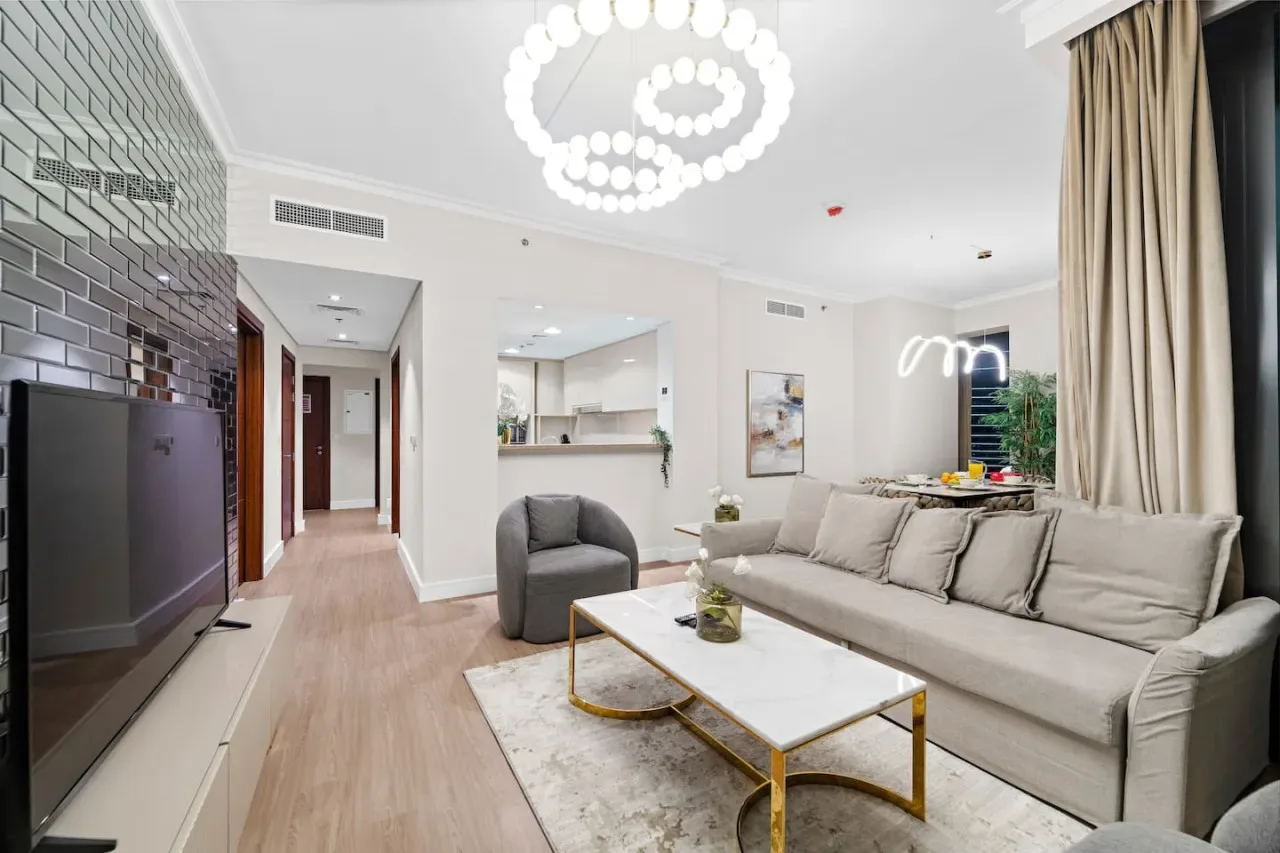 Una sala de estar luminosa con un sofá grande y una mesa de centro con superficie de vidrio.