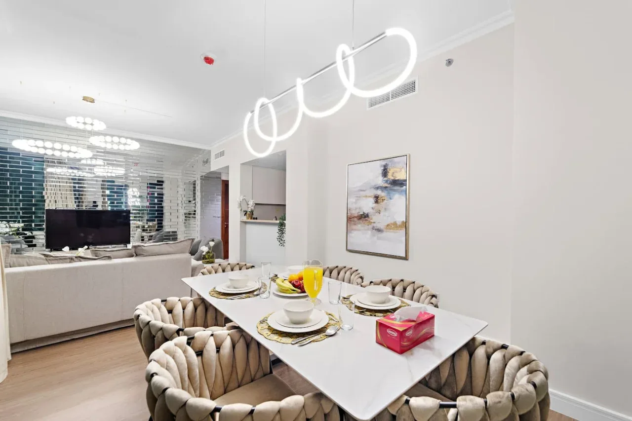 Comedor con una mesa puesta y asientos tapizados, junto a una zona de estar.