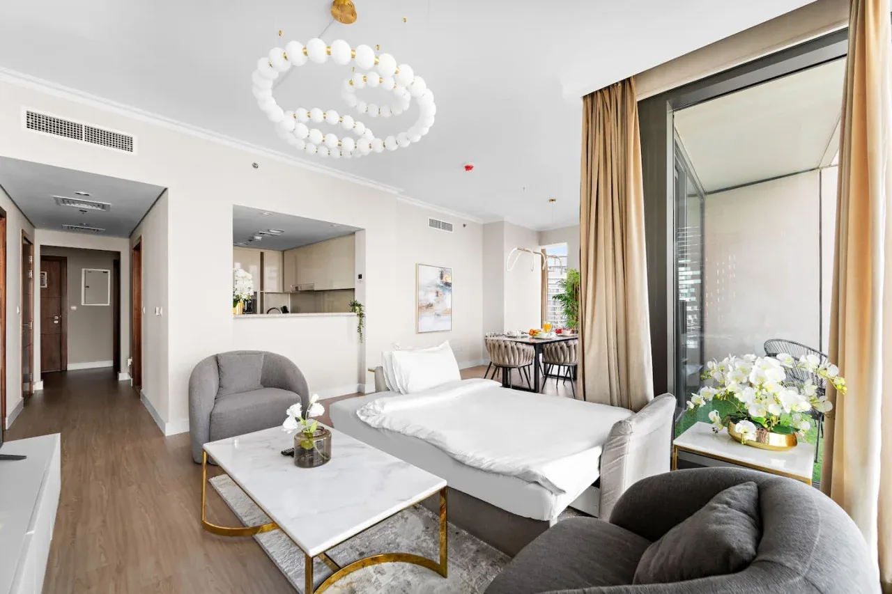 Un dormitorio luminoso con cama, zona de estar y una ventana grande.